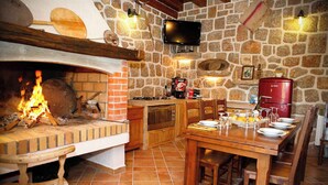 A rustic kitchen with a brick oven, wooden furniture, and stone walls. - Holiday home mit Klimaanlage und Terrasse (Starigrad-Paklenica)