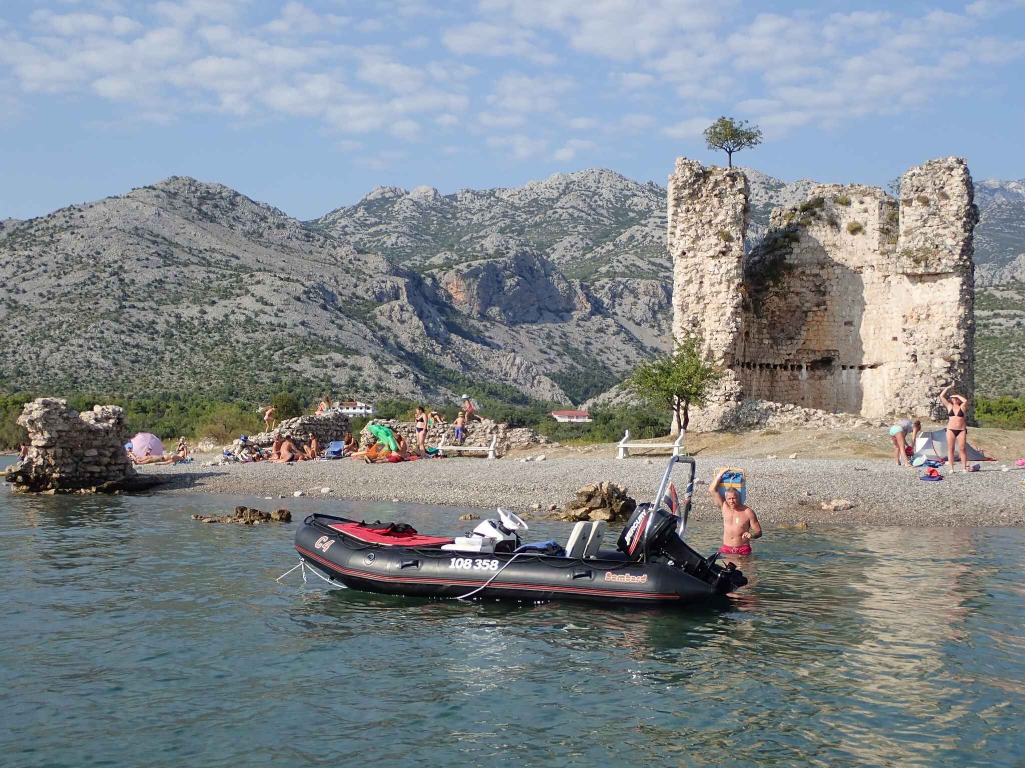 Un bote en un lago tranquilo con montañas al fondo y antiguas ruinas.