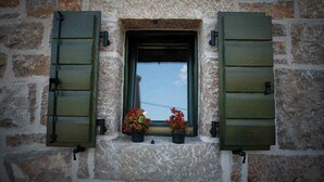 A stone wall with a small window featuring green shutters and two potted plants. - Holiday home mit Klimaanlage und Terrasse (Starigrad-Paklenica)