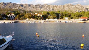 Un puerto deportivo con barcos amarrados, un barco blanco en primer plano y edificios con tejados rojos al fondo.