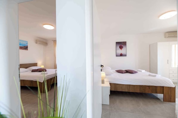 Ett modernt hotellrum med en säng i trä, vita väggar och en taklampa.