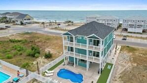A two-story building with a pool, a balcony, and a view of the ocean. - A Wedge Away by Brunswick Vacation Rentals: Near Beach, Great Views, Heated Pool (Ocean Isle Beach)