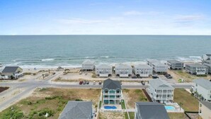 A coastal residential area with beachfront properties, a swimming pool, and a clear view of the ocean. - A Wedge Away by Brunswick Vacation Rentals: Near Beach, Great Views, Heated Pool (Ocean Isle Beach)