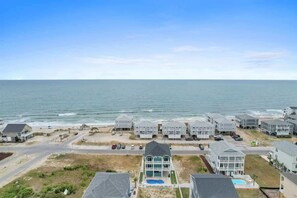 Uma área residencial costeira com imóveis à beira-mar, piscina e vista clara do oceano.
