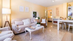A living room with a sofa, coffee table, and a dining area with a table and chairs. - Rincon Dorado by Interhome (Torremolinos)