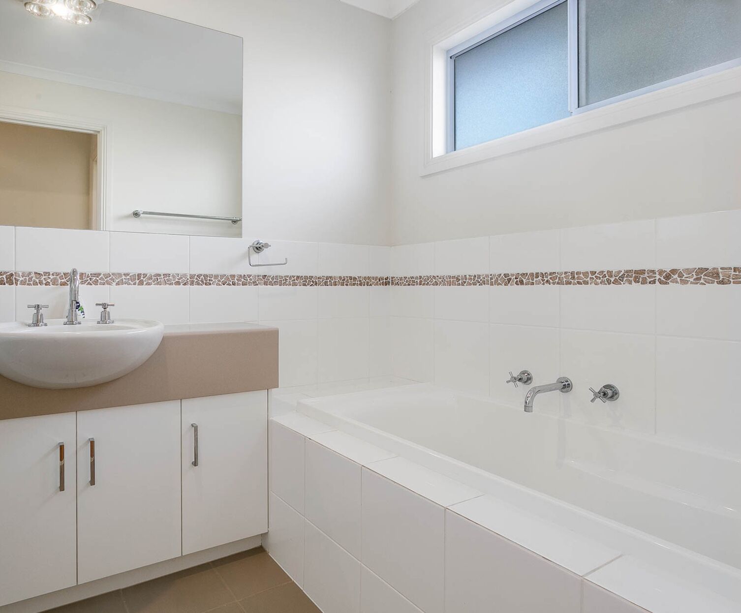 A modern bathroom with a white sink, vanity, and bathtub.
