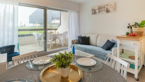 Una sala de estar moderna con comedor, sofá, mesa de centro y puerta corrediza de vidrio que da a un patio exterior.
