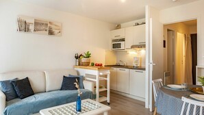 Un espacio habitable compacto con sofá, una pequeña mesa de comedor, kitchenette y zona de comedor.