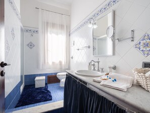 Un baño con lavamanos blanco, un espejo y cortina de ducha.