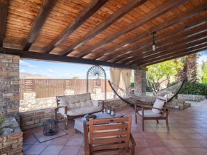 Un patio al aire libre con muros de piedra, muebles de madera y una hamaca.