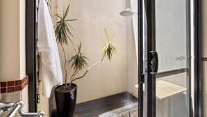 A shower area with a potted plant, a towel hanging on a rack, and a glass door leading to a balcony. - Jacaranda Lane | Sleek & Modern | Central (Margaret River)
