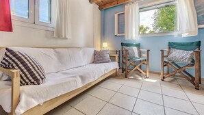 A cozy room with a wooden sofa, two wooden chairs, and a window with curtains. -  Kipi Village Zakynthos (Ζάκυνθος)