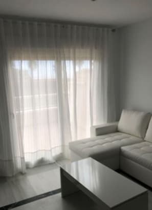 Uma sala de estar moderna com um sofá modular, uma mesa de centro e cortinas leves.