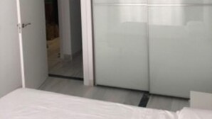 Une chambre à coucher comprenant un lit, une armoire et une porte donnant sur une autre pièce.