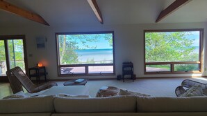 Un salon spacieux doté de grandes fenêtres offrant une vue sur l’océan, d’un canapé confortable et de fauteuils en osier.