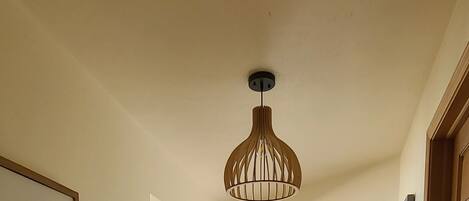 Una habitación con techo de madera, una lámpara colgante y una puerta con marco blanco.