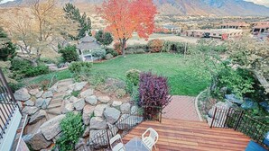 Ein Garten mit einer Holzterrasse, einem Pavillon und Blick auf die Berge.