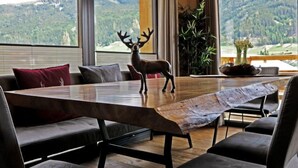 A dining area with a large table, a deer sculpture, and a view of mountains.