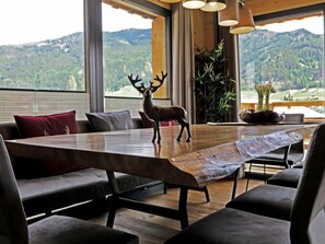 A dining area with a large table, a deer sculpture, and a view of mountains.