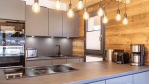 A modern kitchen with a built-in oven, a sink, and a coffee maker.