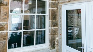 A stone building with a large window and a door. - Painter`s Cottage, a charming cottage in historic Town of Matlock Bath (Derbyshire)