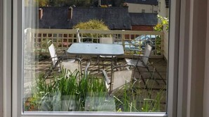 A balcony with a table and chairs, overlooking a green landscape with houses and a cloudy sky. - Painter`s Cottage, a charming cottage in historic Town of Matlock Bath (Derbyshire)