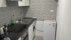 Una cocina funcional con lavabo, lavadora y refrigerador.