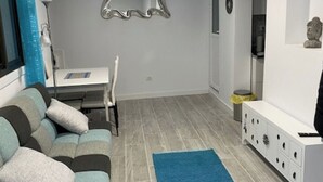 Una sala de estar con un sofá, una mesa de comedor, un espejo y un aparador.