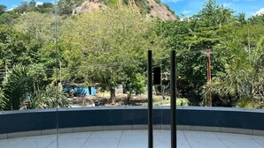 A spacious room with a large window offering a view of a hill with a building on top. - Velan Temple View (Palani)