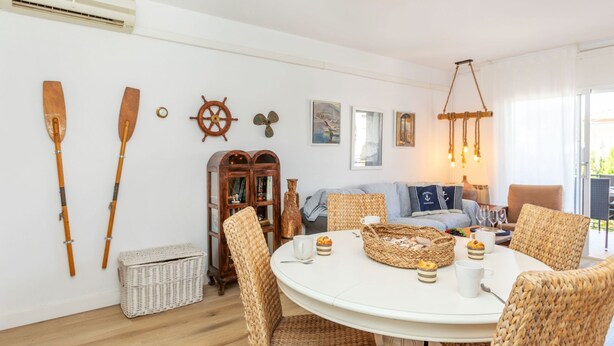 A cozy room with a round table, wicker chairs, a wooden cabinet, and wall-mounted paddles. - Apartment Mirror by Interhome (Cunit)