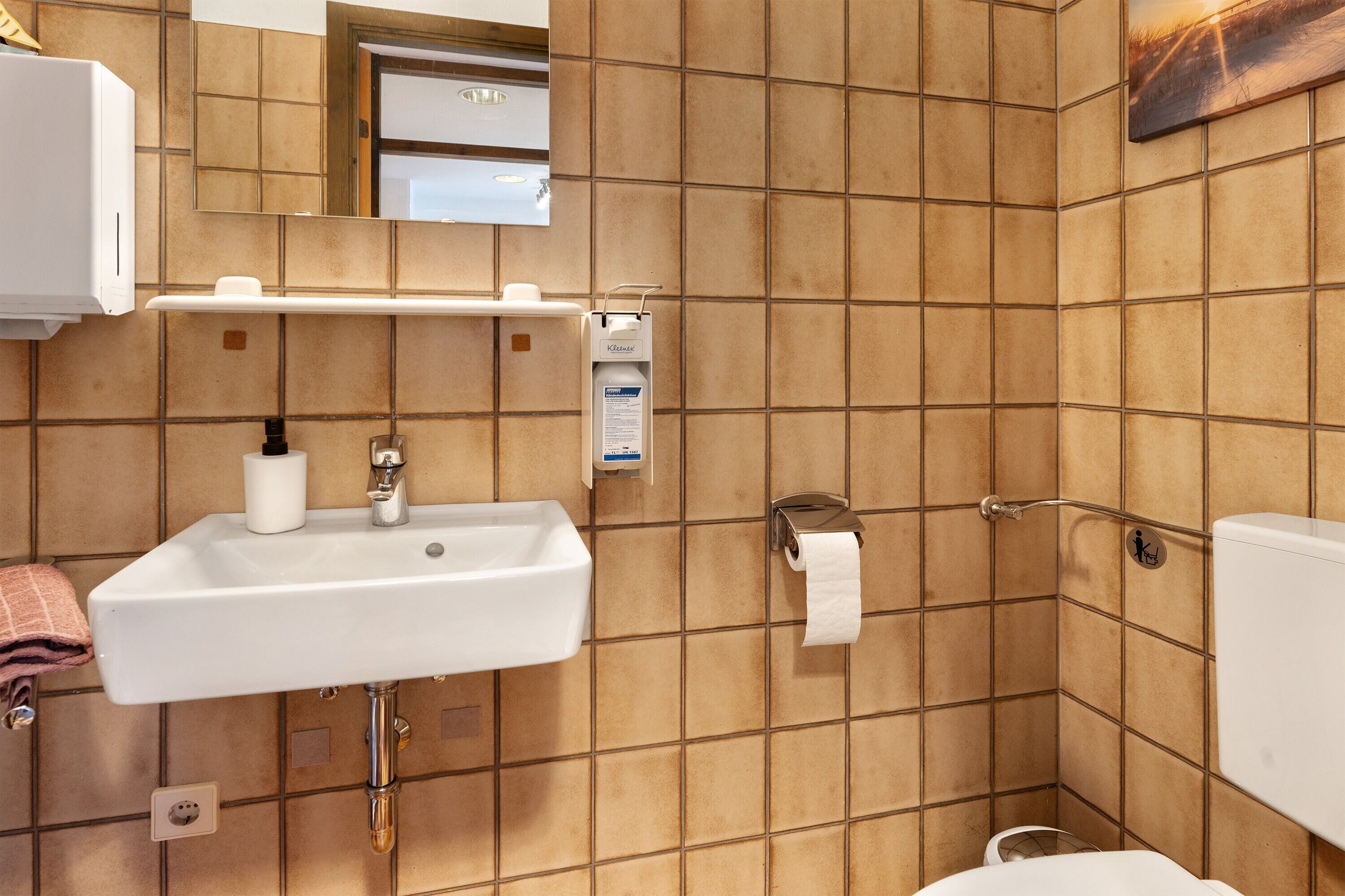 Une salle de bain équipée d’un lavabo, de toilettes et d’un sèche-mains.