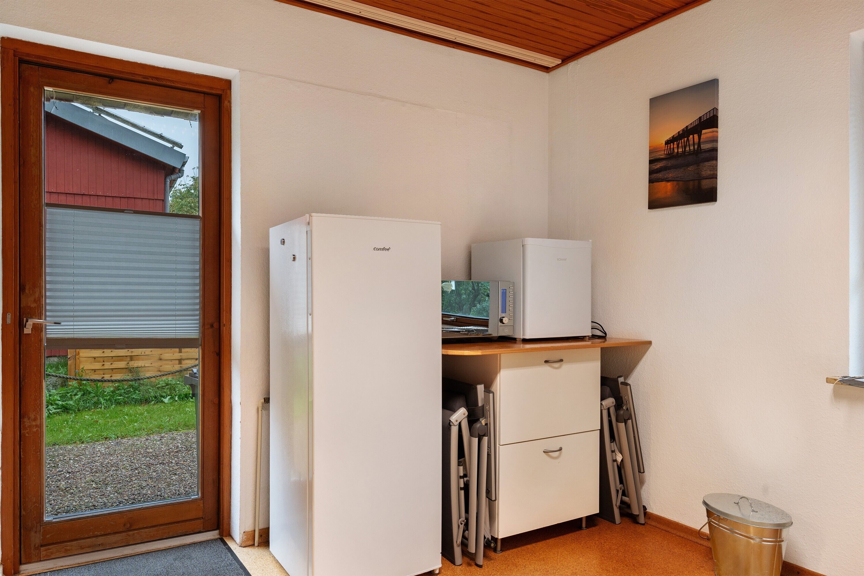 Eine kleine Küche mit Kühlschrank, Mikrowelle und einer Arbeitsfläche.