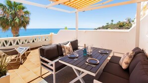 A covered outdoor seating area with a table set for two, overlooking a coastal view. - Panorama Beach by Interhome (Torrox Costa)