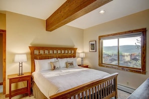 A bedroom with a wooden headboard, a large window with a view, and two bedside tables with lamps. - FREE EV Charger-2 Car Garage-3 enSuites-W/D-DogsOK (Steamboat Springs)