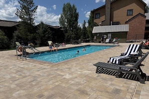 A swimming pool with lounge chairs and a building in the background. - FREE EV Charger-2 Car Garage-3 enSuites-W/D-DogsOK (Steamboat Springs)