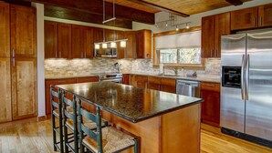 A modern kitchen with wooden cabinets, granite countertops, stainless steel appliances, and a central island with bar stools. - Free EV Charger in 2 Car Garage-3 enSuites-EZ Walk to Resort/Free Town Bus-W/D in Unit-Dogs OK (Steamboat Springs)