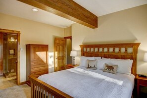 Une chambre à coucher avec une tête de lit en bois, un grand lit, une table de chevet et une armoire en bois.
