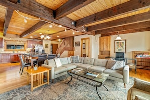 A spacious living area with a large sectional sofa, a dining table, and a kitchen in the background. - FREE EV Charger-2 Car Garage-3 enSuites-W/D-DogsOK (Steamboat Springs)