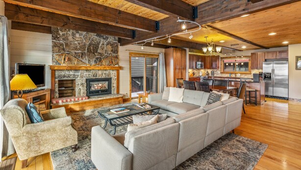 A spacious living room with a large sectional sofa, a fireplace, and a stone accent wall. - Free EV Charger in 2 Car Garage-3 enSuites-EZ Walk to Resort/Free Town Bus-W/D in Unit-Dogs OK (Steamboat Springs)