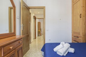 A bedroom with a bed, wooden wardrobe, and a mirror.