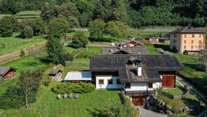 A large house with a sloped roof, a fenced yard, and a small garden. - Chalet 'Agriturismo  Casa Al Campo' with Mountain View, Private Pool and Wi-Fi (Giustino)