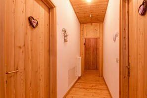 En hall med träpanel på väggarna, dörrar på båda sidor, ett element på väggen och en taklampa.