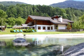 A house with a pool, surrounded by a wooden fence, and a mountain backdrop.