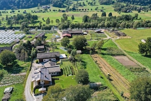 Ett flygbildsbild av ett lantligt område med hus, gröna fält och ett växthus.