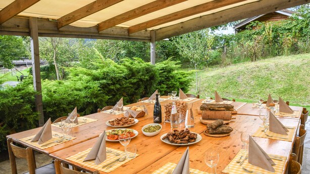 An outdoor wooden table set for a meal with various dishes, glasses, and napkins. - Chalet 'Agriturismo  Casa Al Campo' with Mountain View, Private Pool and Wi-Fi (Giustino)