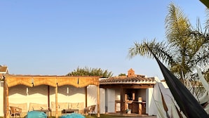 A swimming pool with a patio area, a covered seating area, and a building with a tiled roof. - Chalet "Casa Juan Arias" Close to the Sea with Pool, A/C, Wi-Fi, Garden & Terrace (Conil de la Frontera)