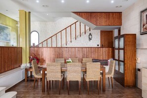 A dining area with a wooden staircase, wicker chairs, and a dining table. - Chalet "Casa Juan Arias" Close to the Sea with Pool, A/C, Wi-Fi, Garden & Terrace (Conil de la Frontera)