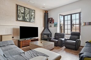 Una sala de estar con chimenea, sofá, sillón y televisor de pantalla plana.