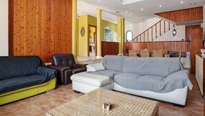 A spacious living area with a wooden-paneled wall, a staircase, and a sofa set. - Chalet "Casa Juan Arias" Close to the Sea with Pool, A/C, Wi-Fi, Garden & Terrace (Conil de la Frontera)