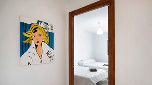 A bedroom with a bed, a bedside table, and a painting on the wall.